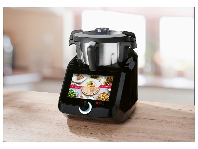 Schwarze Küchenmaschine mit Touchscreen, der Modi und Rezepte anzeigt, auf Holzarbeitsplatte.