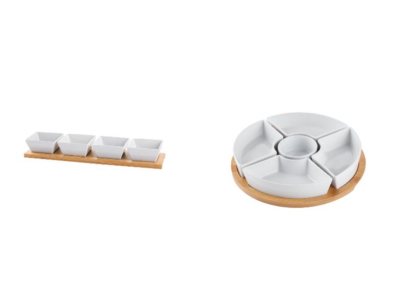 Eine runde und rechteckige Servierplatte aus weißem Porzellan mit Holzsockel.