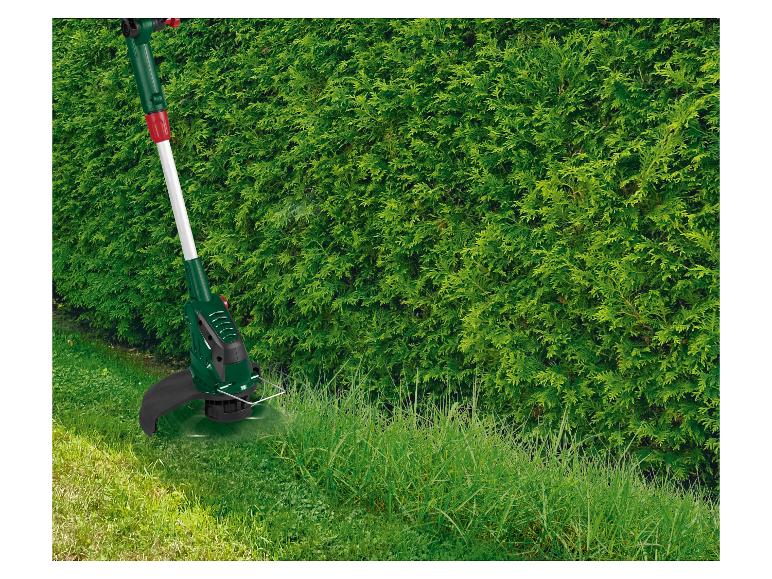 Rasentrimmer schneidet hohes Gras an einer Hecke.