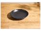 Eine matt-schwarze Keramikschale auf einem hellen Holztisch.