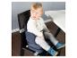 Baby in einem tragbaren Sitzerhöher auf einem Esszimmerstuhl neben einem weißen Tisch.