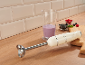 Cremefarbener Stabmixer mit Smoothie, Beeren und Schneidebrett auf einer Holzoberfläche.