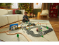 Kind spielt mit Holzeisenbahn und Straßenmatte auf einem Teppich in einem festlichen Wohnzimmer.