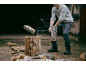 Mann hackt Holz mit einer Axt, mit fliegenden Splittern