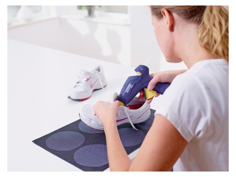 Frau benutzt LIVARNO® Heißklebepistole zum Kleben von Turnschuhen.