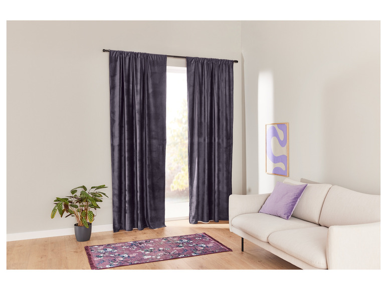 Dunkelgraue Vorhänge, ein weißes Sofa und ein rosa Teppich mit Blumenmuster.