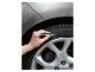 Hand schreibt mit einem weißen Marker auf einen Autoreifen