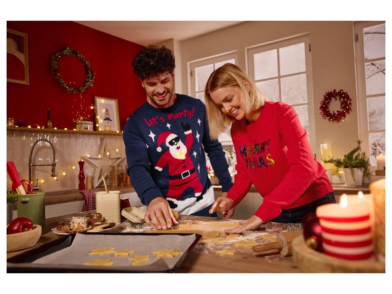 Ein lächelndes Paar trägt Weihnachtspullover und sticht Plätzchen in der Küche aus.