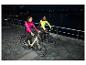 Zwei Personen in CRIVIT Thermo-Hybridjacken fahren nachts Fahrrad