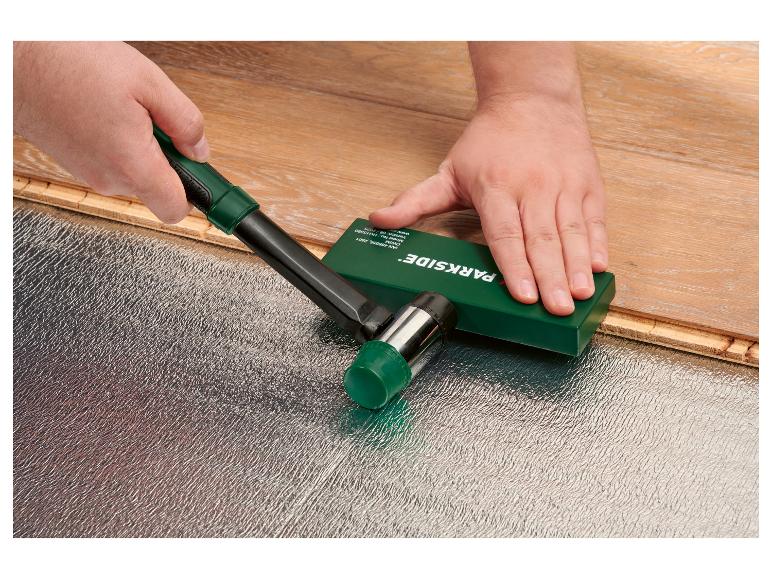 Ein Arbeiter verlegt Laminatböden mit einem Gummihammer und einem Schlagklotz.