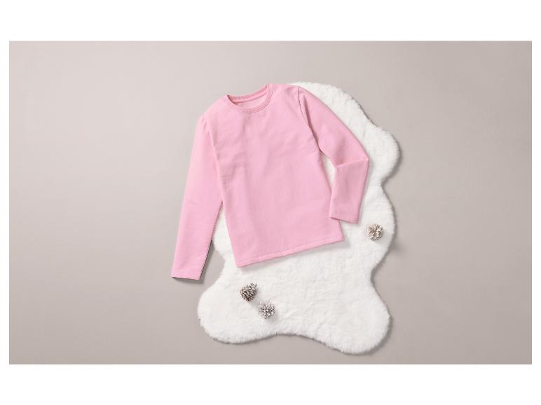 Ein rosa Langarmshirt auf einem weißen Fellteppich.