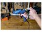 Mann lädt eine blaue LIVARNO® Klebepistole »EG340« mit einem Klebestift in einer Werkstattumgebung.