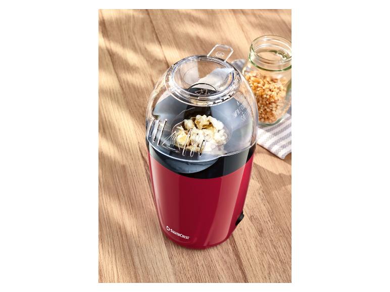 Rote Silvercrest Popcornmaschine mit Popcorn und Maiskörnern auf einem Holztisch.