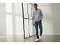 Mann in grauem Langarmshirt, blauen Jeans und weißen Sneakern.