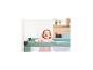 Lachendes Baby spielt in einem grünen Reisebett.