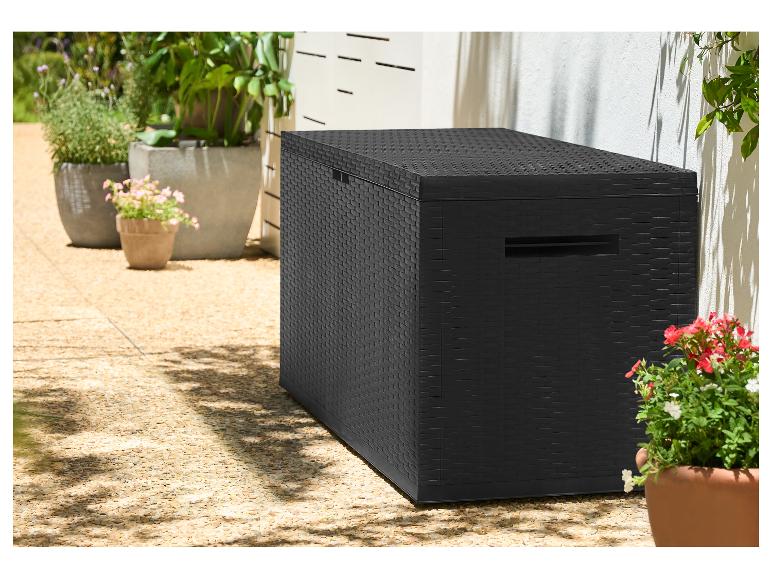 Schwarze Aufbewahrungsbox in Rattan-Optik auf einer Terrasse mit Topfpflanzen.
