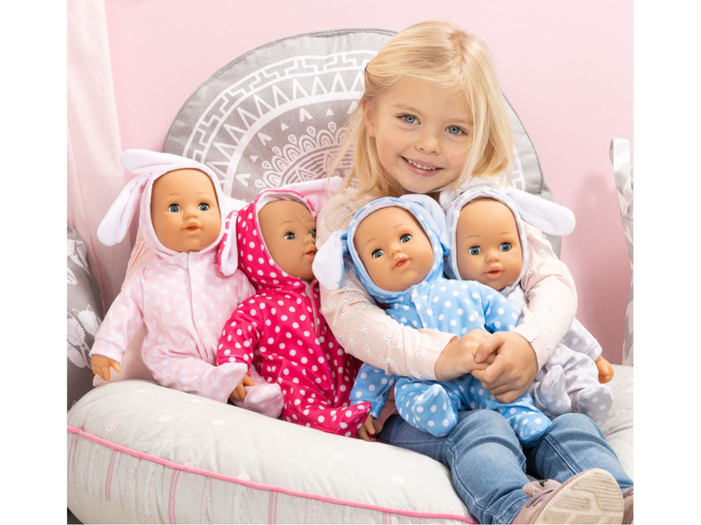 Ein Mädchen hält vier Puppen fest, die alle einen Hasenkostüm tragen.