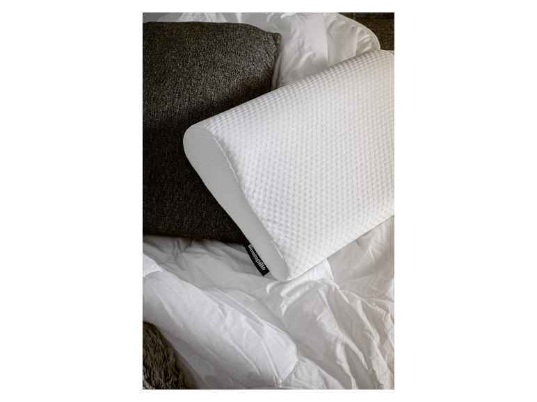 Weißes Dunlopillo Kissen auf einem Bett mit einer weißen Decke und einem braunen Kissen.