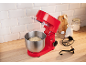Rote Küchenmaschine mit Teig in einer Schüssel, Backzutaten und Zubehör auf einer Holztheke.
