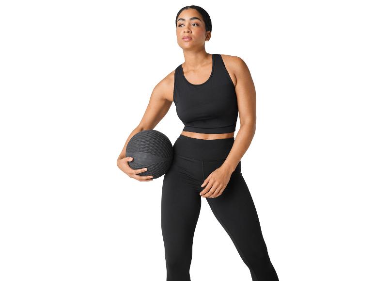 Frau in schwarzer Sportkleidung mit einem Medizinball.