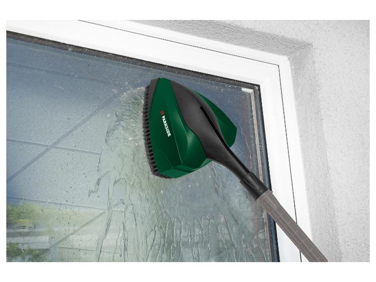 Eine grüne Parkside Fensterwaschanlage mit Bürste reinigt ein Fenster.