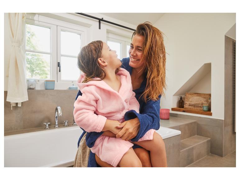 Eine Frau und ein Mädchen in Bademänteln im Badezimmer.