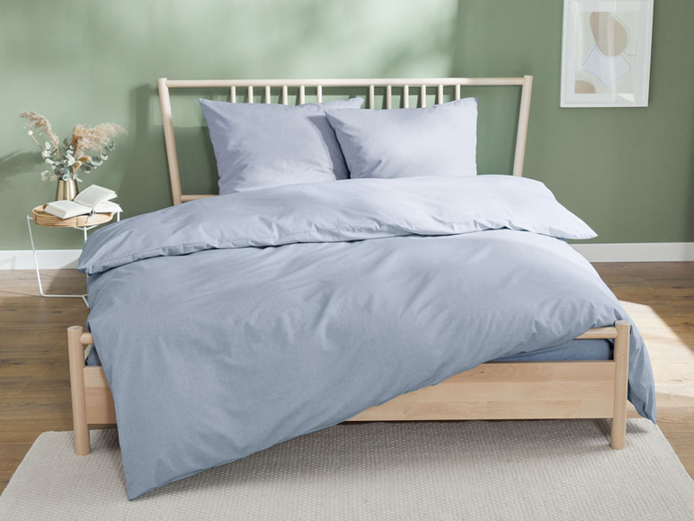 Hellblaue Bettwäsche auf einem Holzbettgestell.