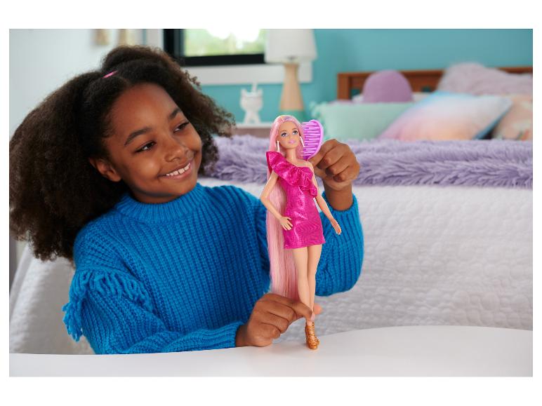 Ein lächelndes Mädchen hält eine Barbie-Puppe mit langen rosa Haaren und einer Bürste.