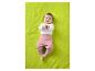 Baby in weißem Langarmshirt und rosa Hose liegt auf einer grünen Decke.