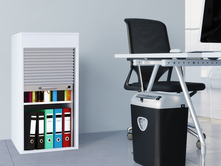 Ein weißer Schreibtisch mit einer Rolltür, einem Aktenvernichter und Ringordnern.