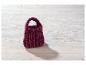 Handgestrickte bordeauxrote Handtasche auf weißem Holz.