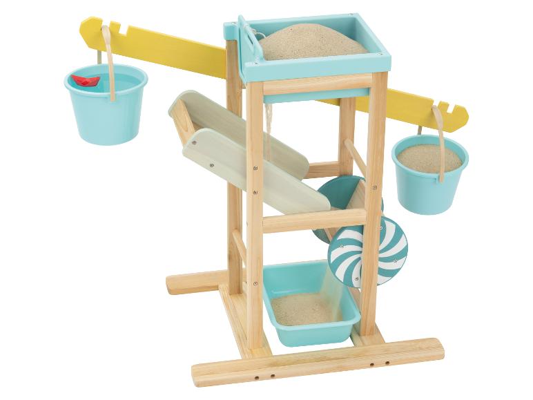 Hölzerne Sand- und Wasserspielstation mit Eimern, Sand, Wasser und einem roten Papierboot.