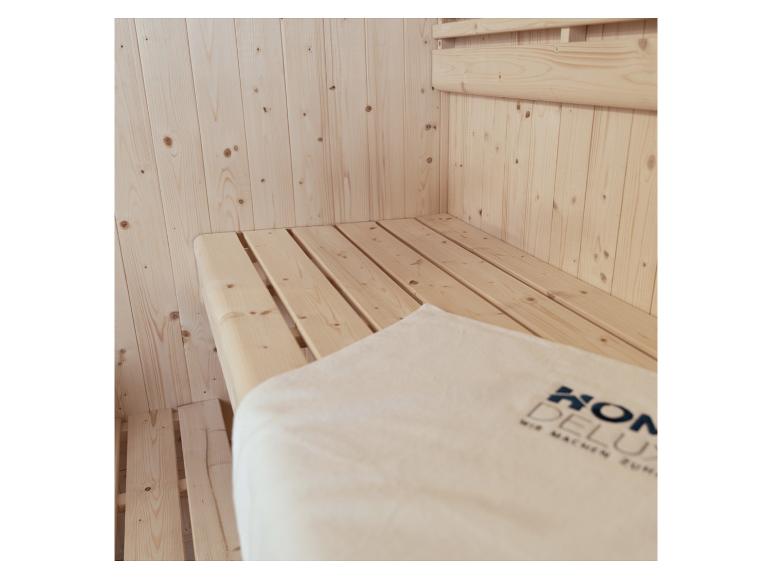 Helle Holzsaunabank mit einem weißen Handtuch mit dem „KON DELUX“-Logo.