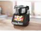 Schwarze smarte Küchenmaschine mit Touchscreen, der Rezepte anzeigt, auf einem Holztisch.