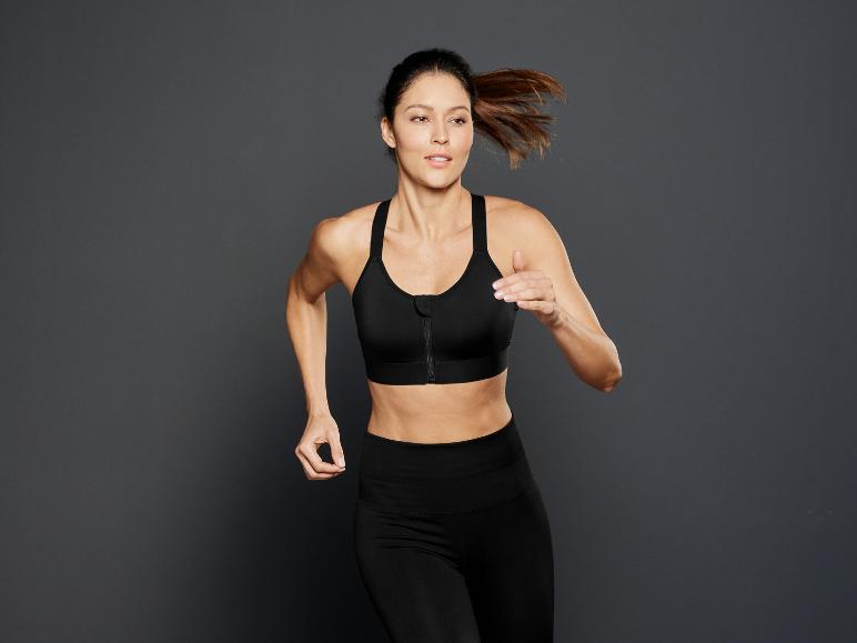 Eine Frau in einem schwarzen Sport-BH und Leggings läuft