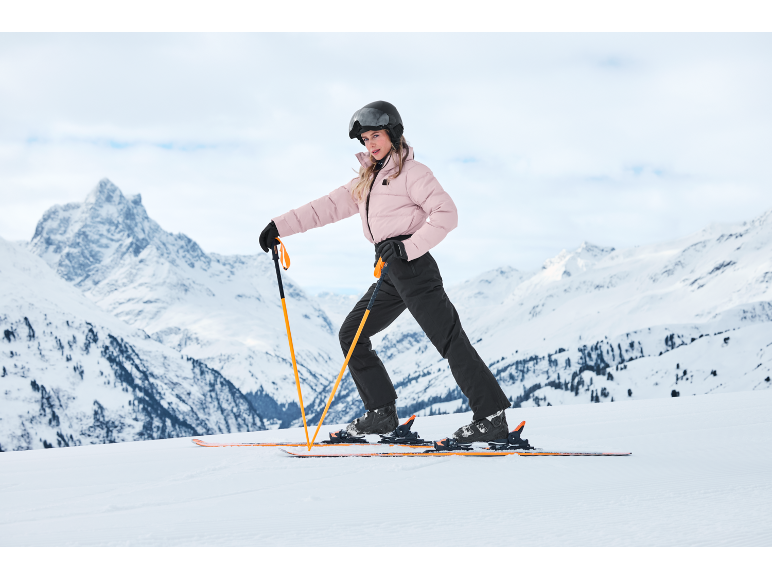 Frau in rosa Skijacke und schwarzer Hose beim Skifahren in den Bergen
