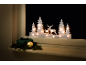 Leuchtende Weihnachts-Fenstersilhouette mit Hirschen und Tannen auf einer Fensterbank