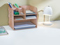 Ein Holzorganizer mit Büroartikeln wie Stiften, Notizbüchern und einer Lampe.