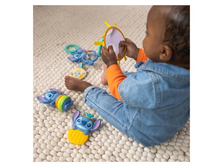 Baby spielt mit Zeichentrickfiguren und einem Spiegel auf einem Teppich.