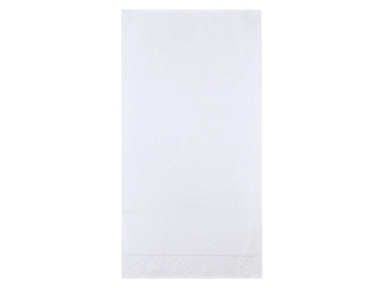 Weißes Handtuch mit dezentem Muster am unteren Rand.