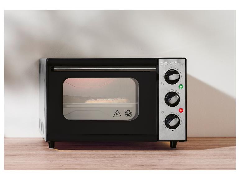 Schwarzer SilverCrest Mini-Ofen mit Edelstahl-Bedienfeld auf einem Holztisch.