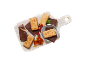 Holzschneidebrett mit schokoladenüberzogenen Keksen mit Stadtmotiven, roten Johannisbeeren und Karamellstücken.