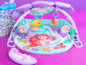 Eine Little Mermaid Baby-Spielmatte mit einer Spielunterlage, einem Bogen mit Spielzeug und einem Kissen.
