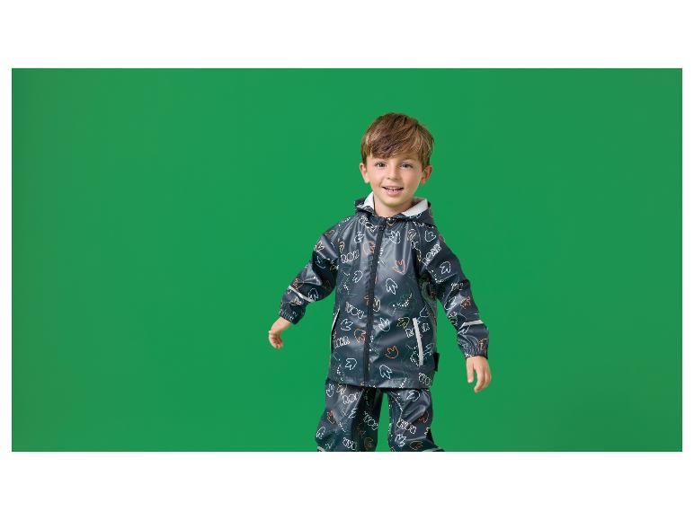 Glücklicher Junge in dunkelblauem Regenanzug mit Dinosaurier-Print.