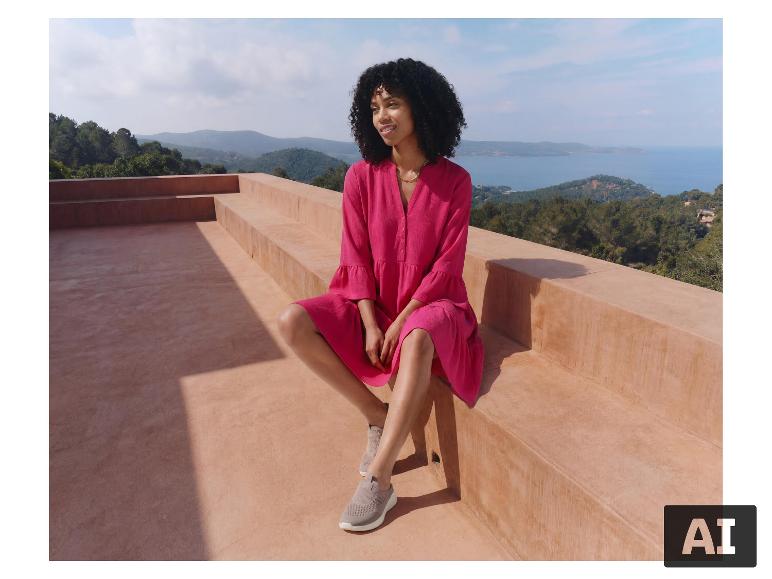 Eine Frau in einem rosa ESMARA® Damen Tunika-Kleid sitzt auf einer Terrasse. [KI-generiertes Bild]