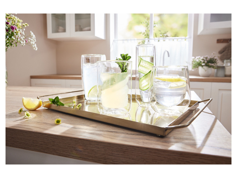 Gläser mit Zitrone und Gurke auf einem goldenen Tablett.