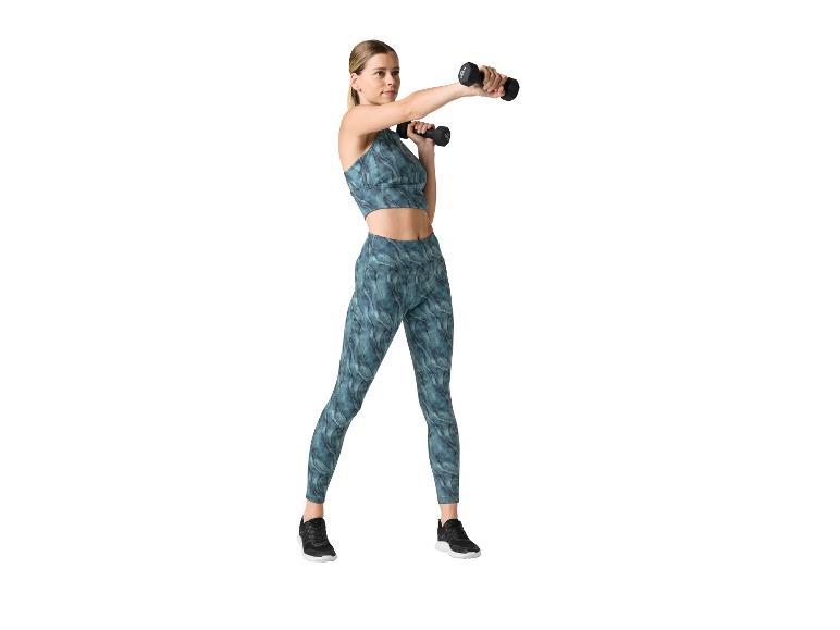Frau in Sport-BH und Leggings mit Hanteln