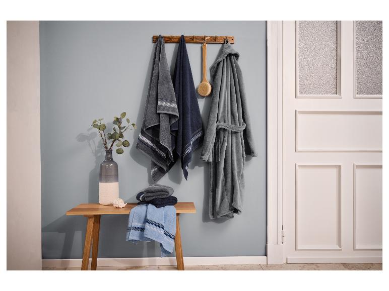 Badezimmer mit Handtüchern, Bademantel und einer Holzbank mit Vase und Muschel.