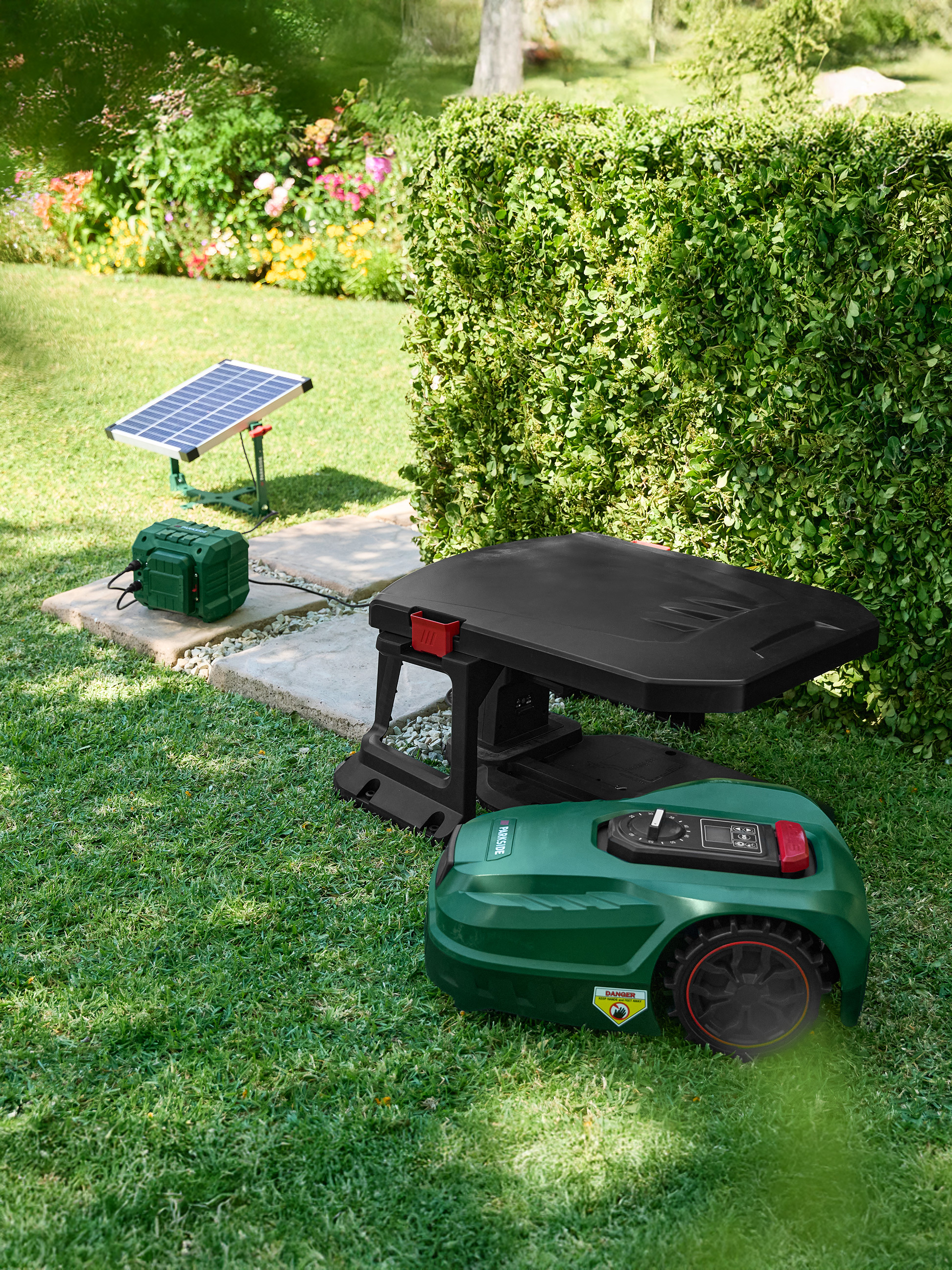 Mähroboter mit Ladestation und Solarpanel in einem Garten.
