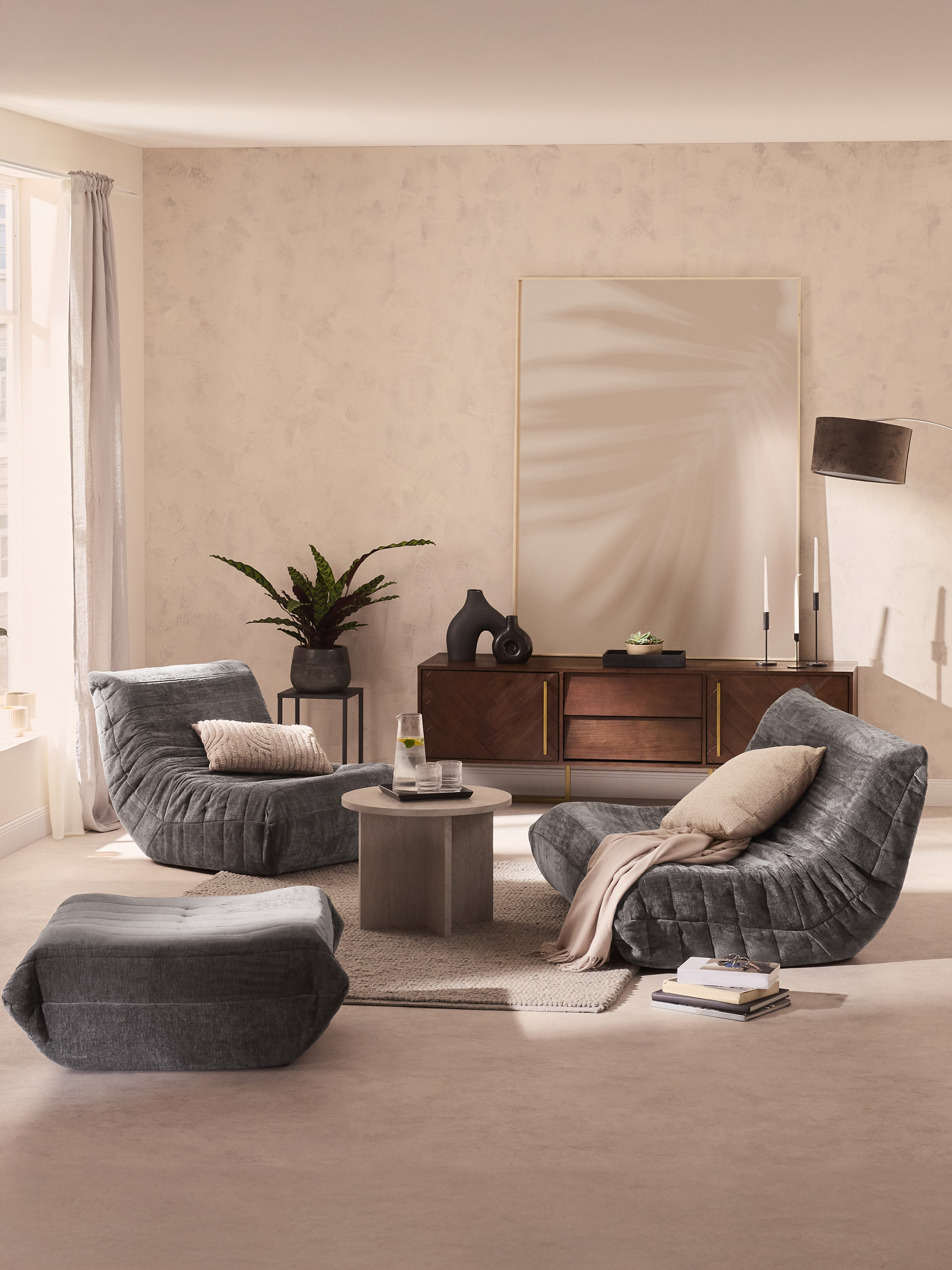 Modernes Wohnzimmer mit bequemen grauen Sesseln, Couchtisch und Holzkommode.
